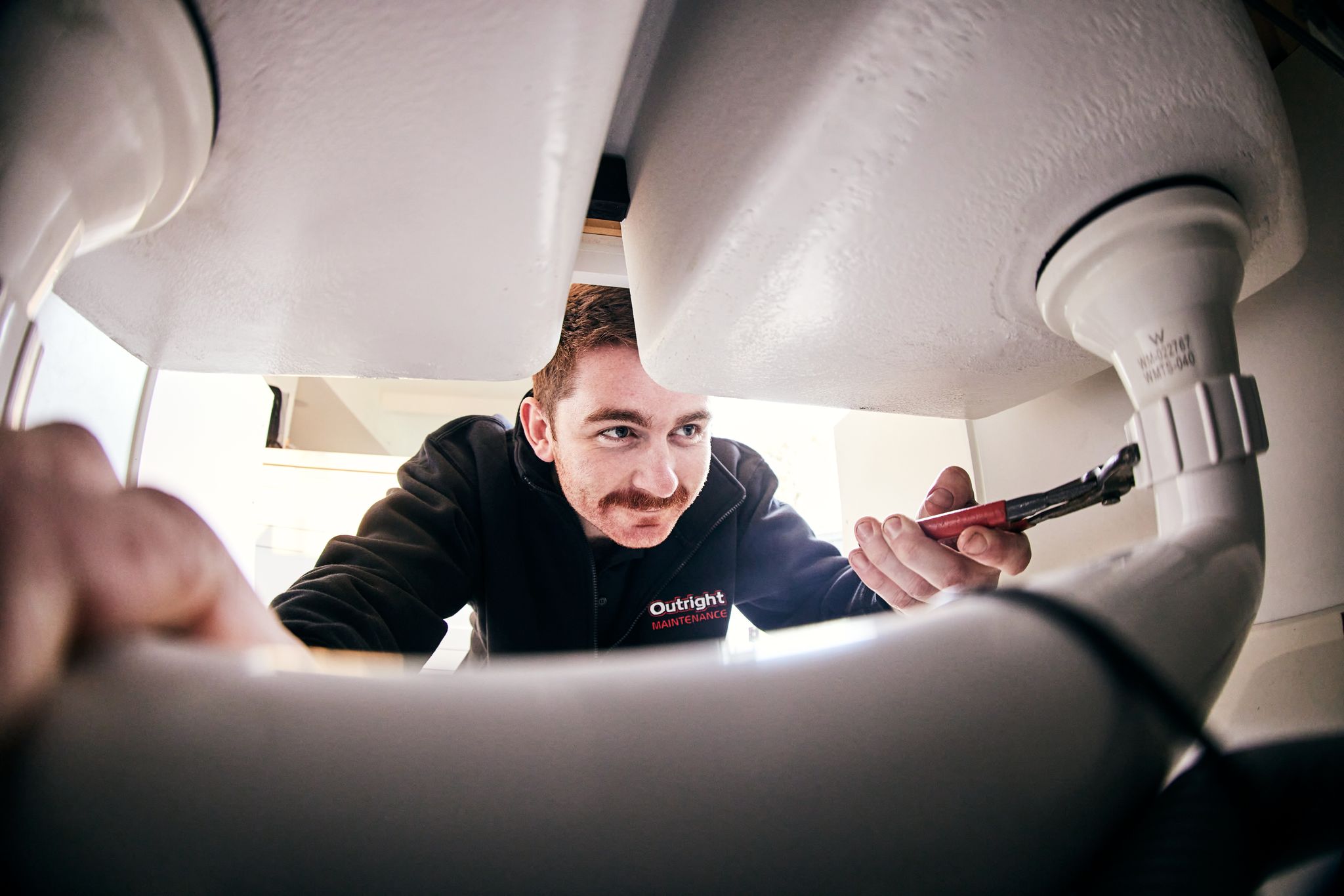 Outright Maintenance plumber fixing a drain.