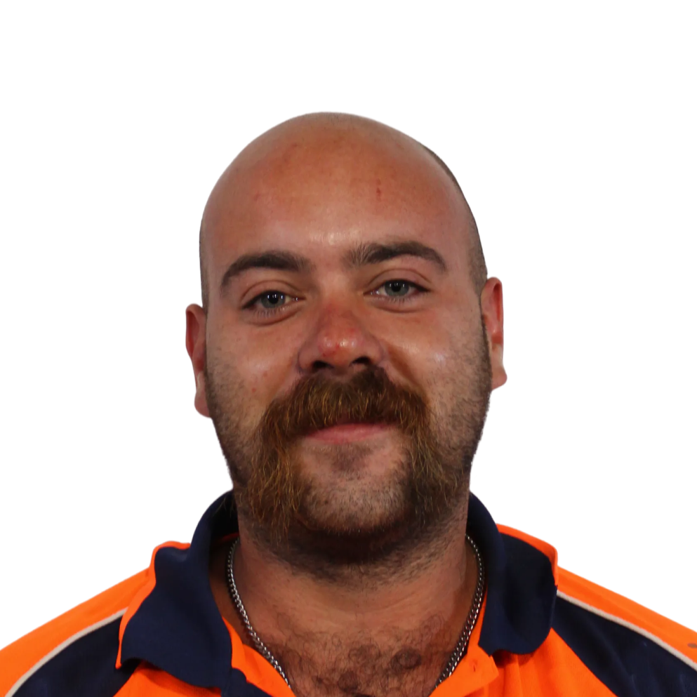 Portrait of a bald man with a thick mustache wearing an orange and navy collared shirt.