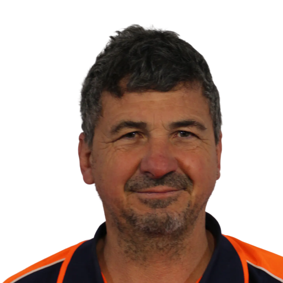 Middle-aged man with short dark hair and stubble wearing a navy and orange collared shirt.