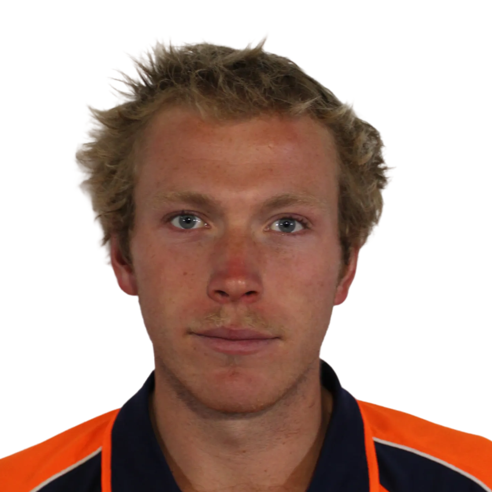 Young man with tousled light brown hair and blue eyes wearing an orange and navy blue collared shirt.