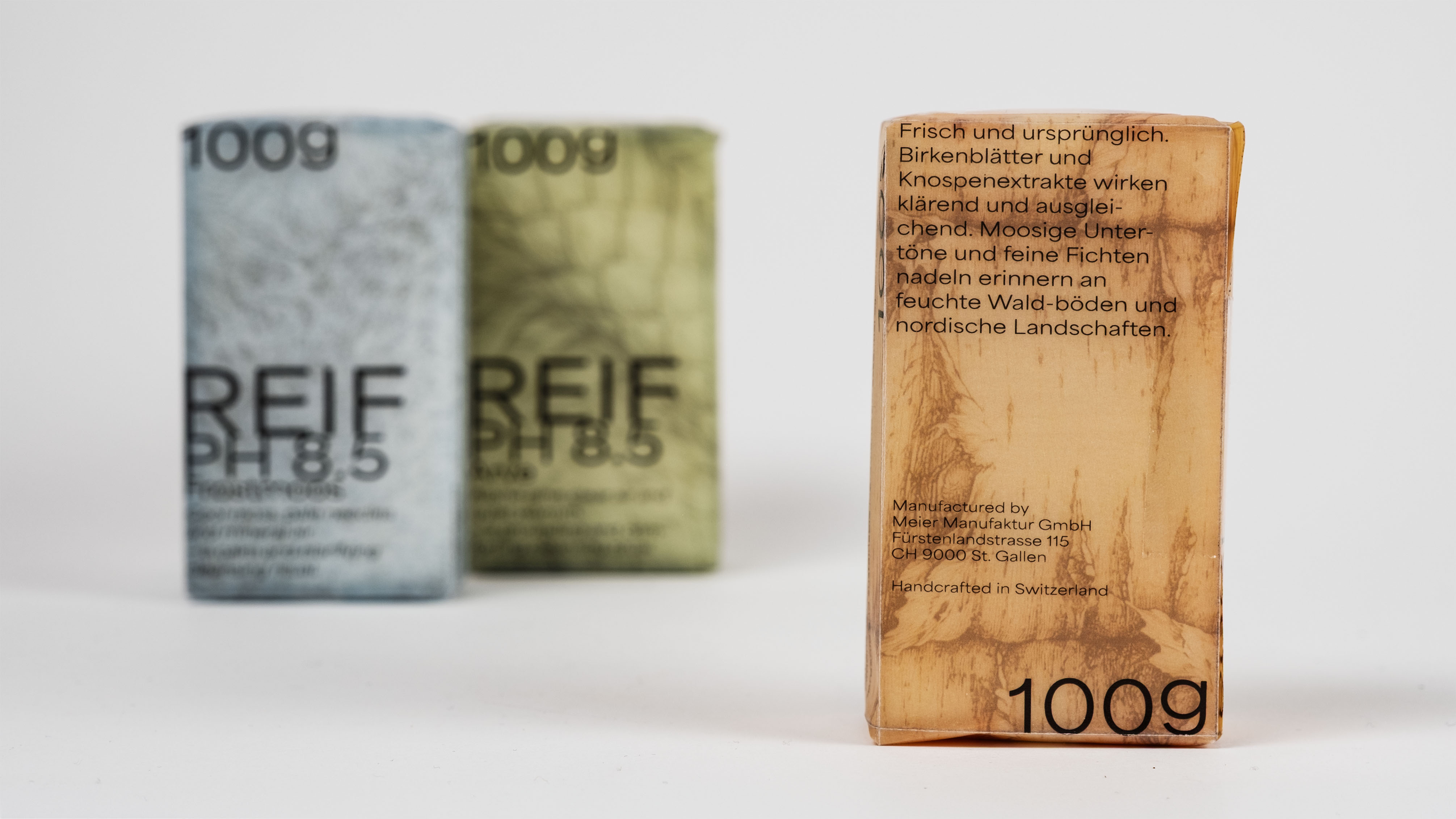 Three rectangular soap bars with natural, earthy packaging in beige, green, and blue, featuring German text and 100g weight on a white background.