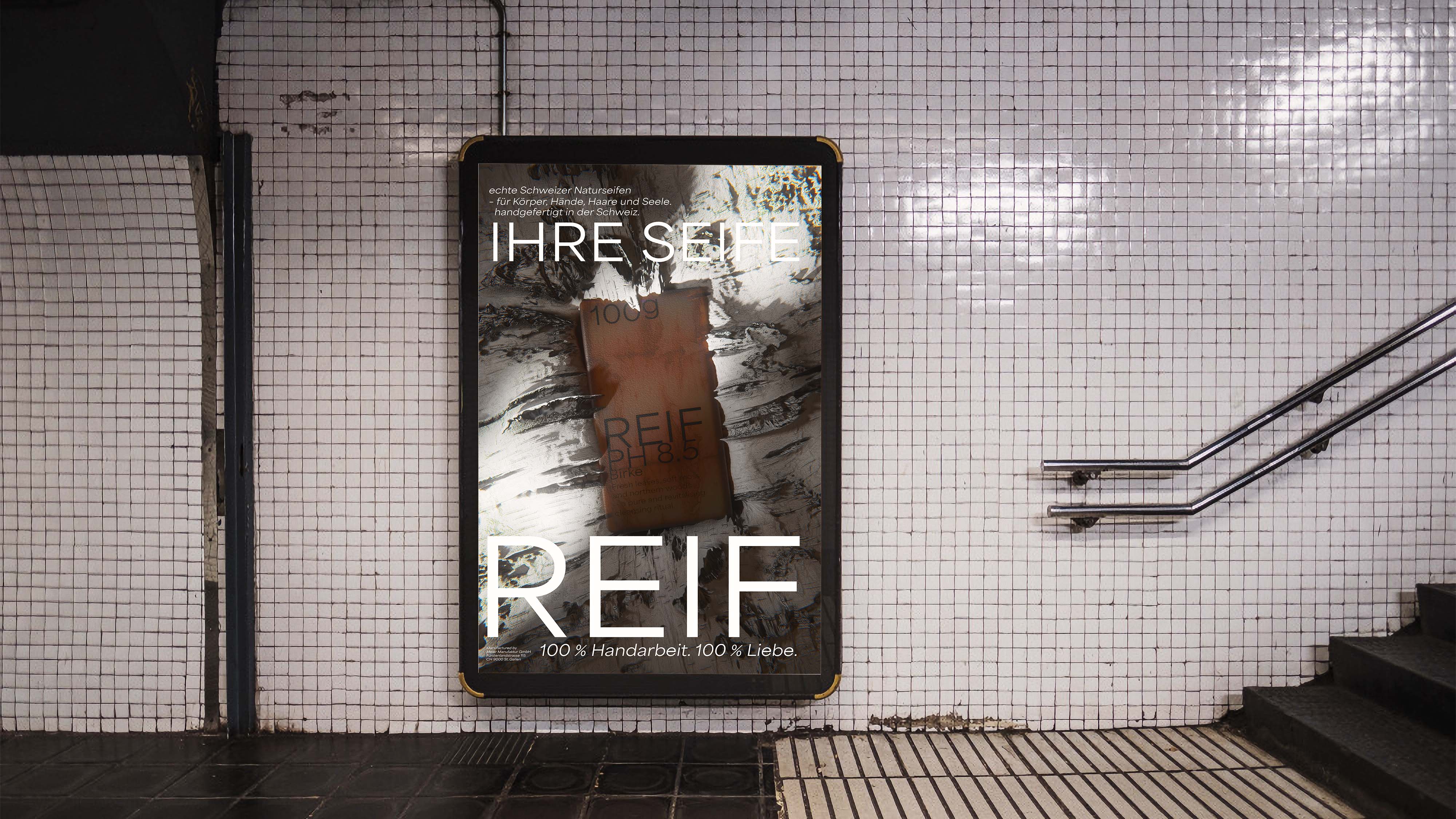 Subway station wall with white tiles, a poster advertising Swiss natural soap reading 'IHRE SEIFE REIF' with a bar of soap image, and a staircase with metal handrails.