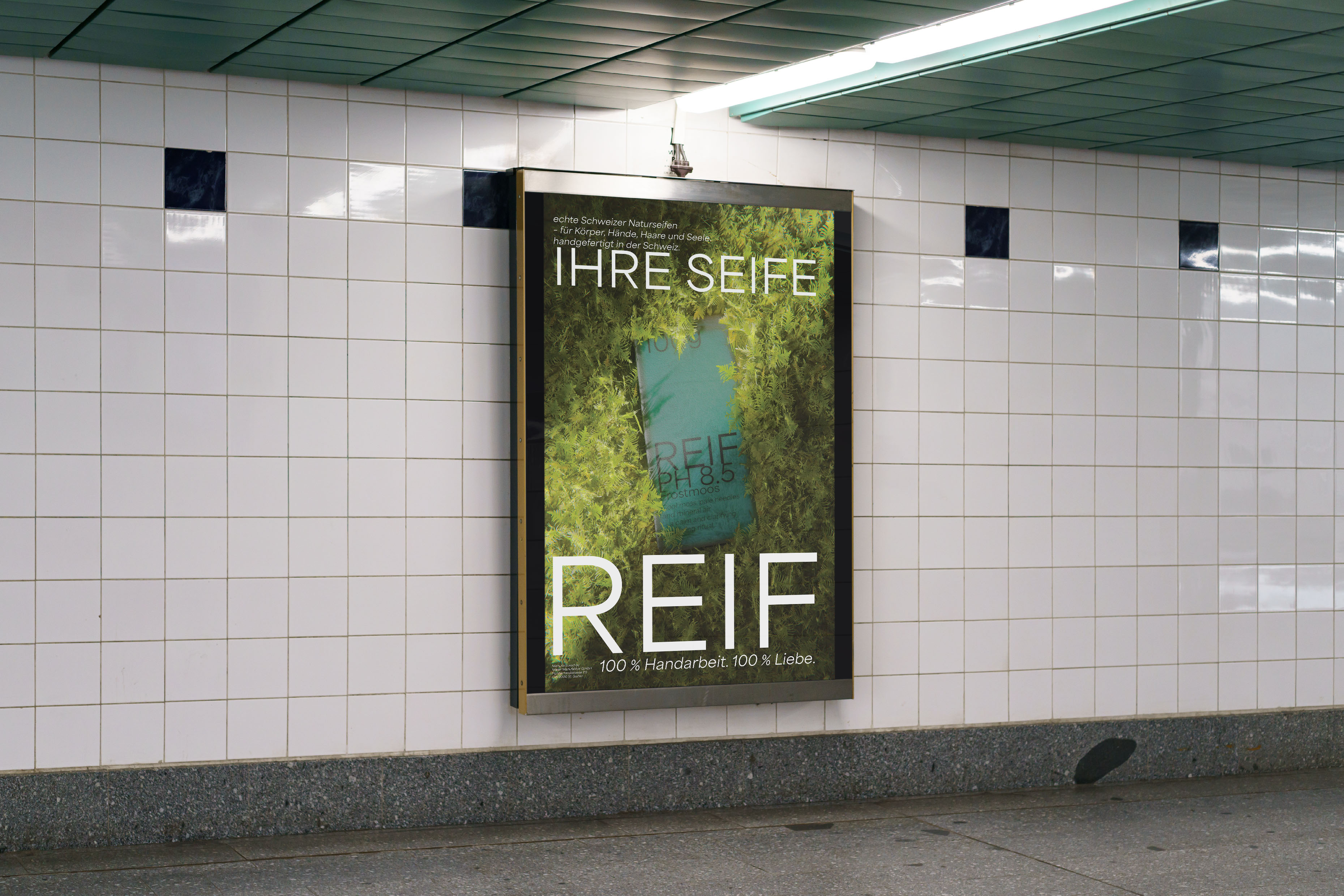 Advertisement in tiled subway station showing a natural soap bar surrounded by green moss with German text promoting handmade soap.