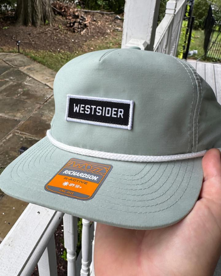 Sage green rope hat with a black and white WESTSIDER patch and white rope braid