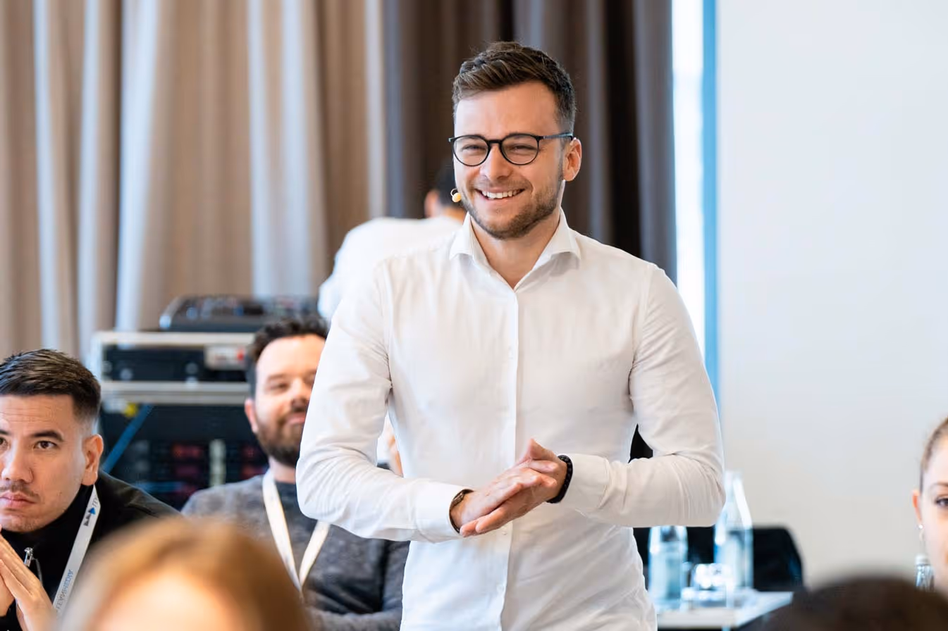Paul Gerngross, der in der Webdesign Agentur in Fürth arbeitet, trägt ein weißes Hemd und lacht.