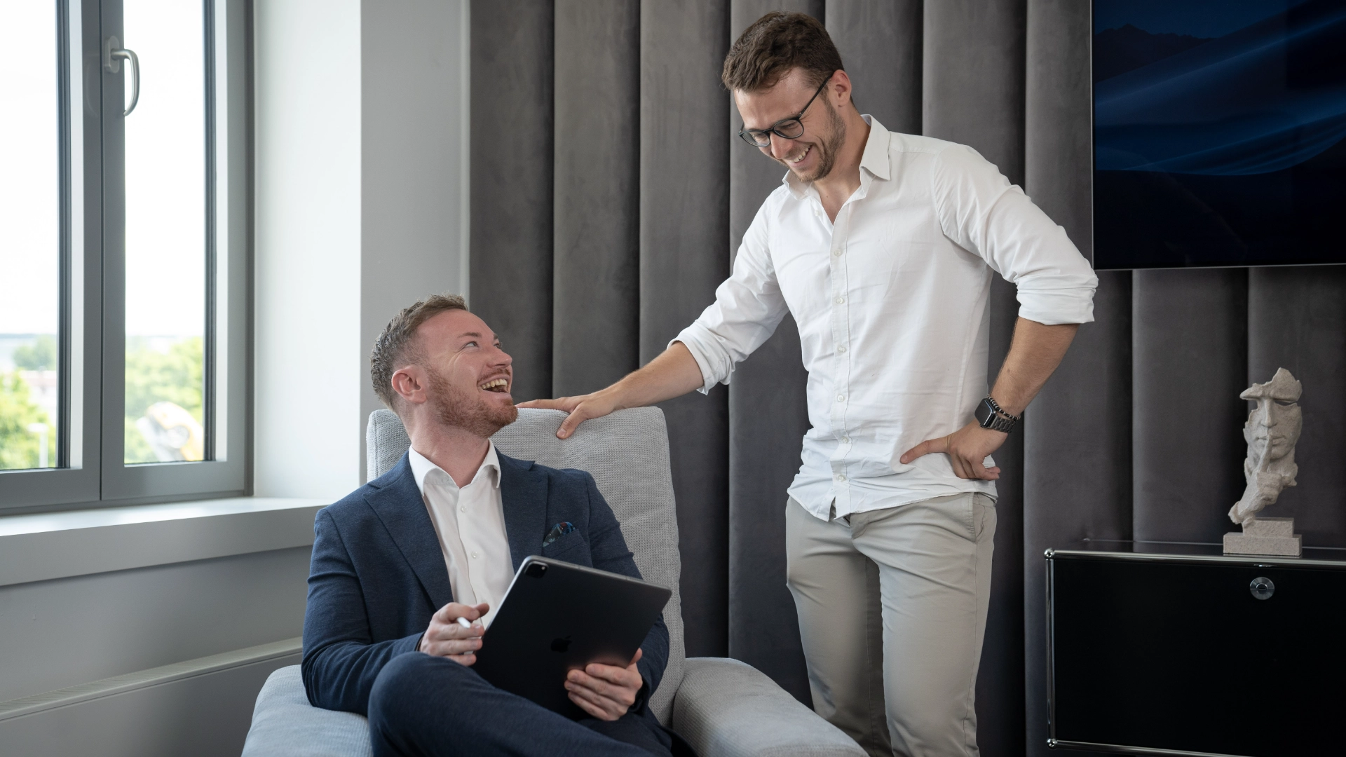 Ein Bild von Paul Gerngroß, der dem Kunden in einem Sessel ein Konzept erklärt und dabei lacht. Paul Gerngroß hat eine Werbeagentur in Fürth gegründet.