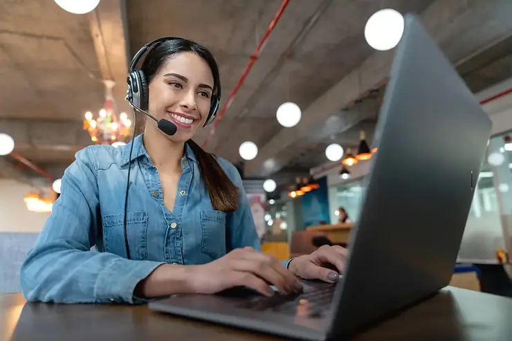 Virtual assistant companies representative providing support via laptop and headset in a co-working office setting.