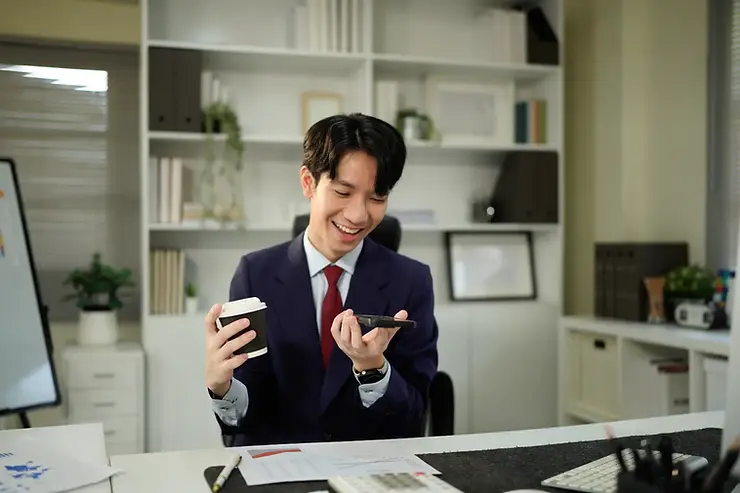 Virtual assistants providing remote support, shown using a smartphone while seated at a professional office desk.
