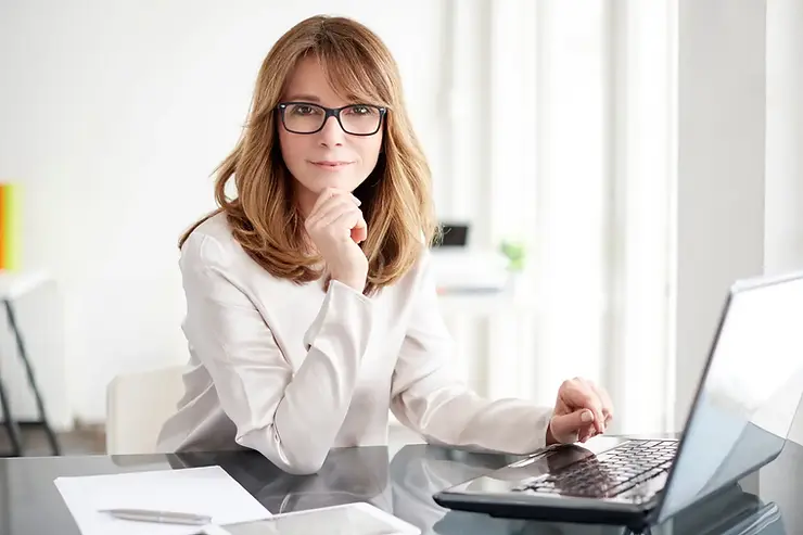 American online assistants offering support while working on a laptop at a glass desk in a home office.