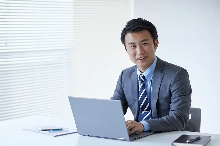 USA outsourcing solutions provider using a laptop in a formal office while discussing work.