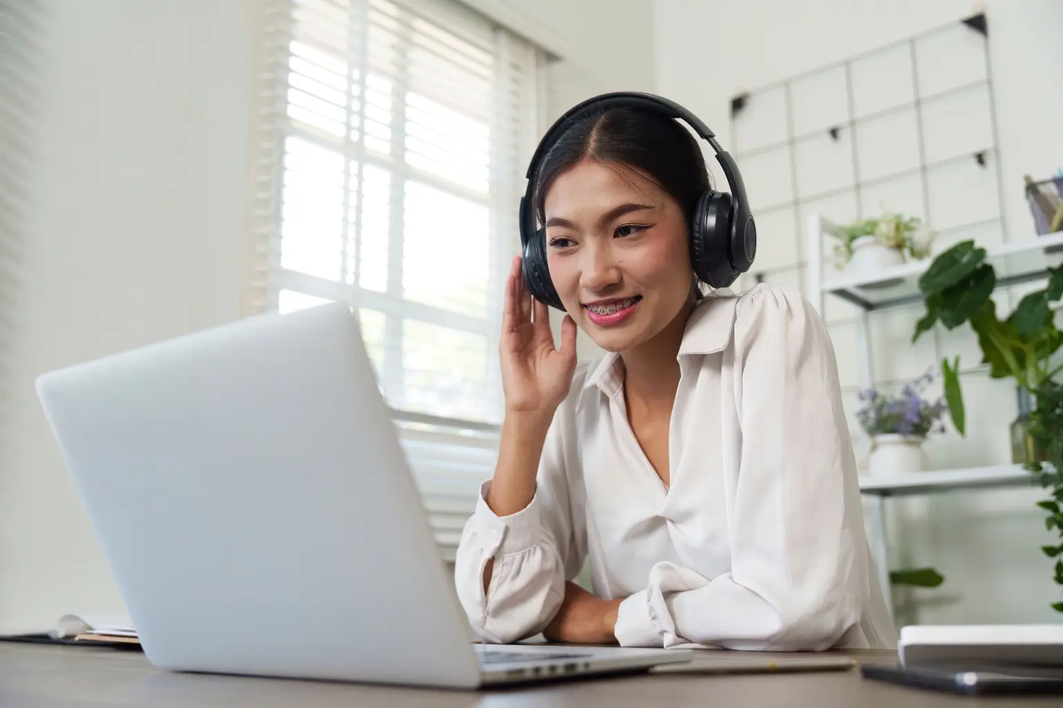 Virtual assistant in the USA attending an online meeting with headphones while working from a home office.