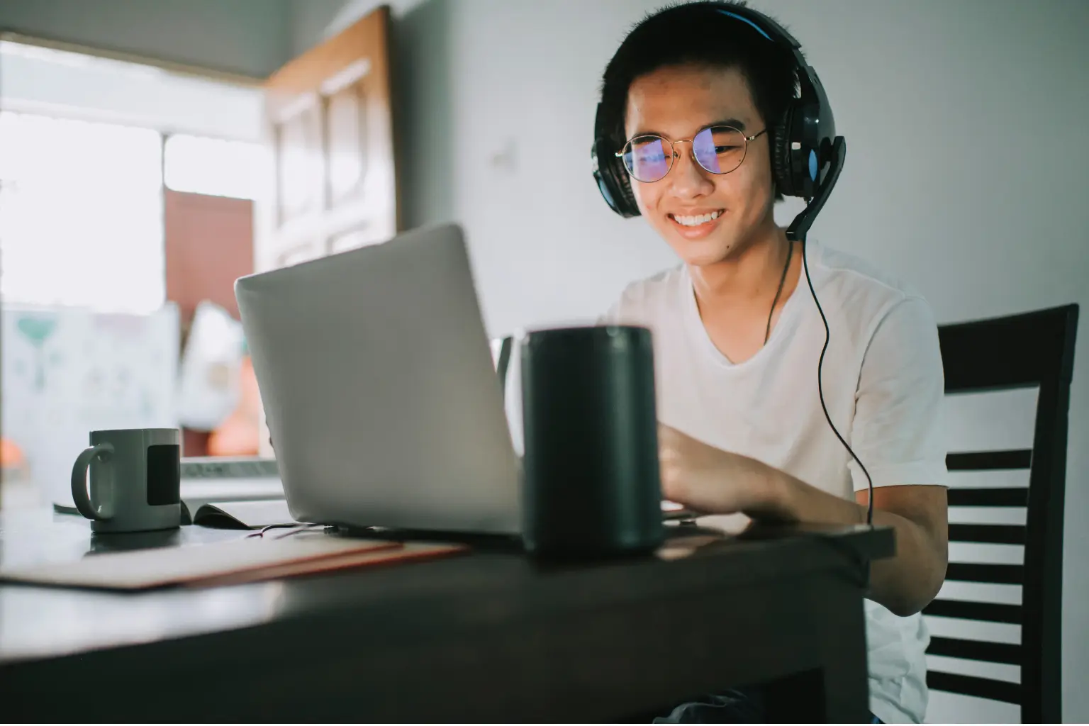 Remote VA in a wheelchair wearing a headset and adjusting a monitor while taking notes at a well-lit office desk.