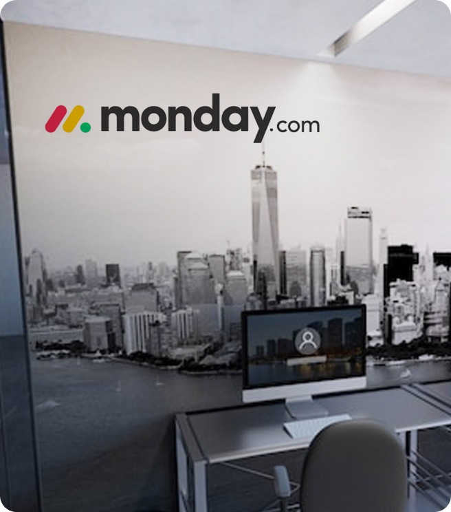 Office workspace with a modern desk, chair, computer, and a large black-and-white cityscape mural on the wall featuring a skyline with high-rise buildings.