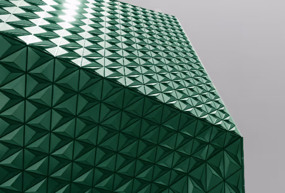 Close-up view of a green building facade covered with a geometric pattern of glossy, pyramid-shaped tiles.