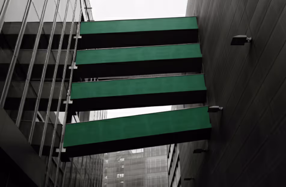 Four green rectangular bridges connecting two modern buildings over a narrow alley.