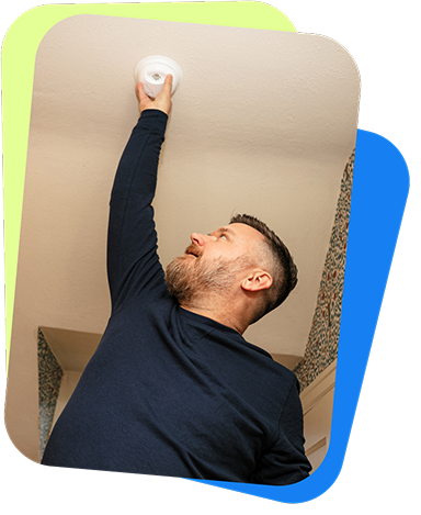 Man reaching to change battery in smoke detector on ceiling
