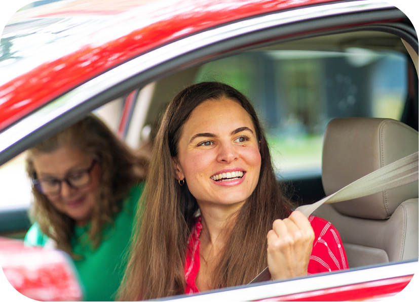 Young woman in drivers seat of car with older woman in passenger seat