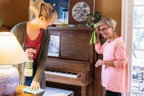Young woman helping senior woman clean up the house