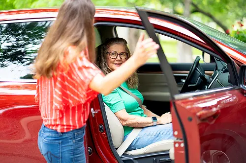 Young woman giving car ride to senior woman