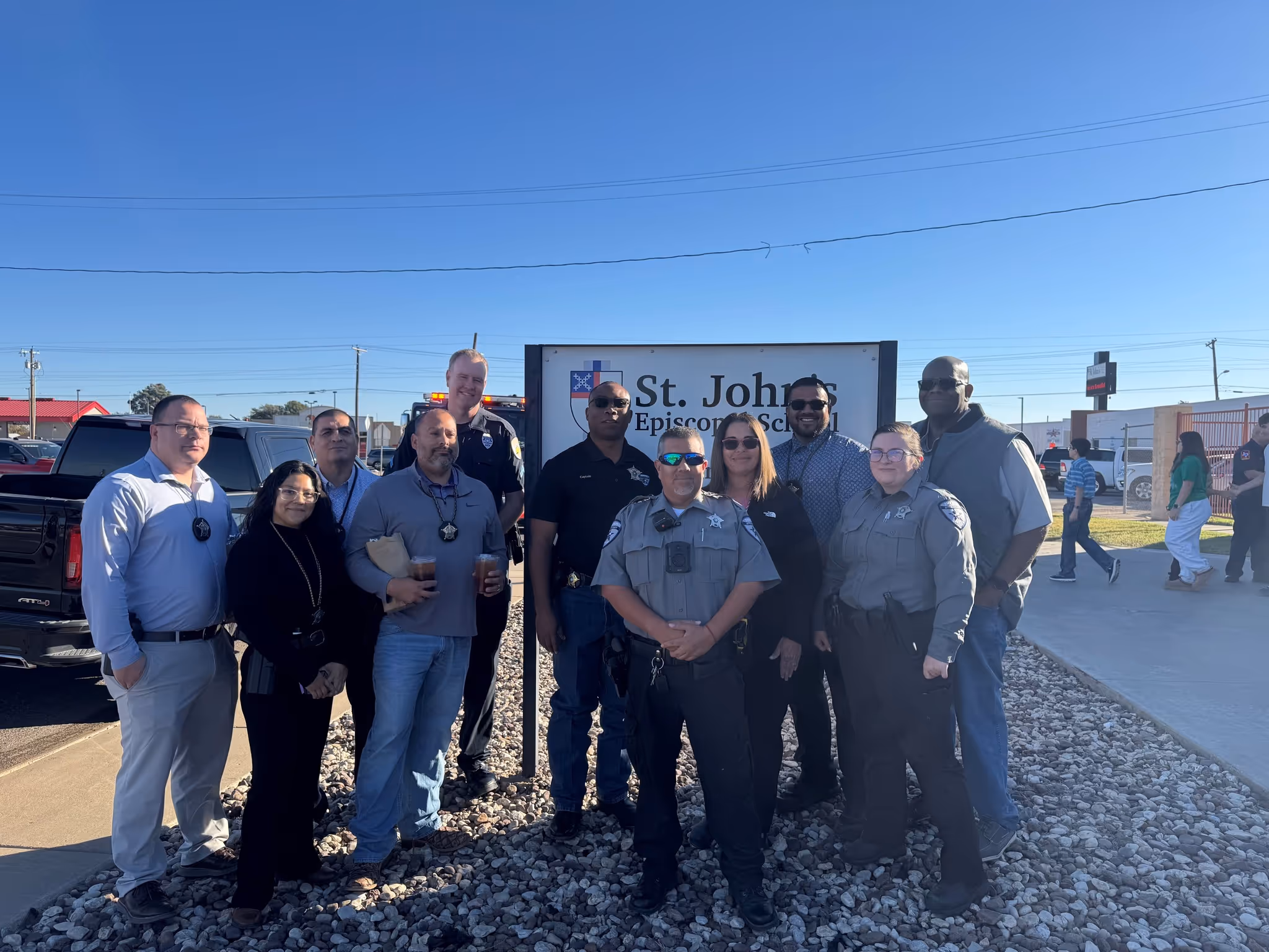 Group of Odessa officers standing together in front of the St. John’s Episcopal School sign during a community event.
