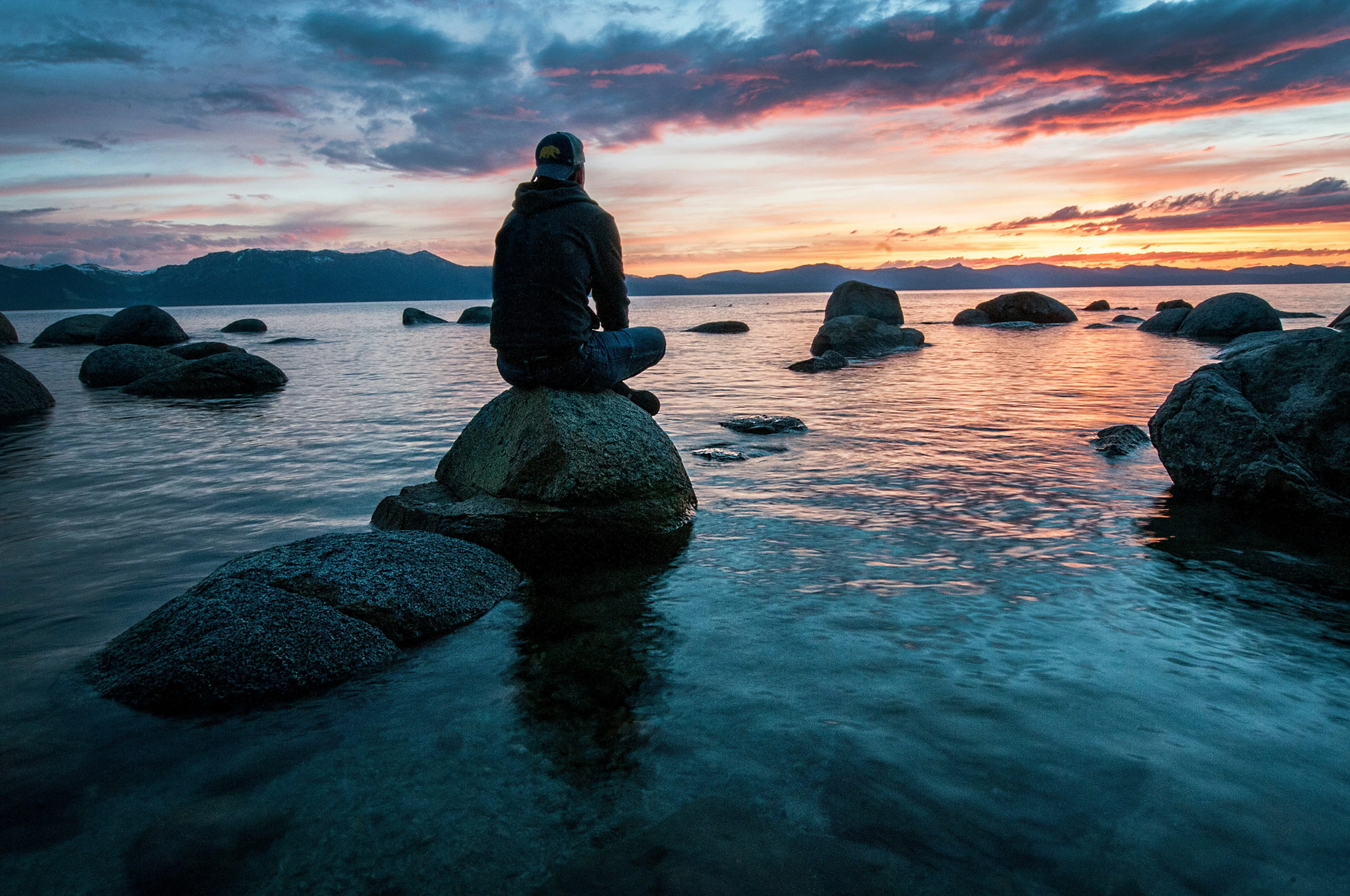 Man sitting on a rock contemplatively image