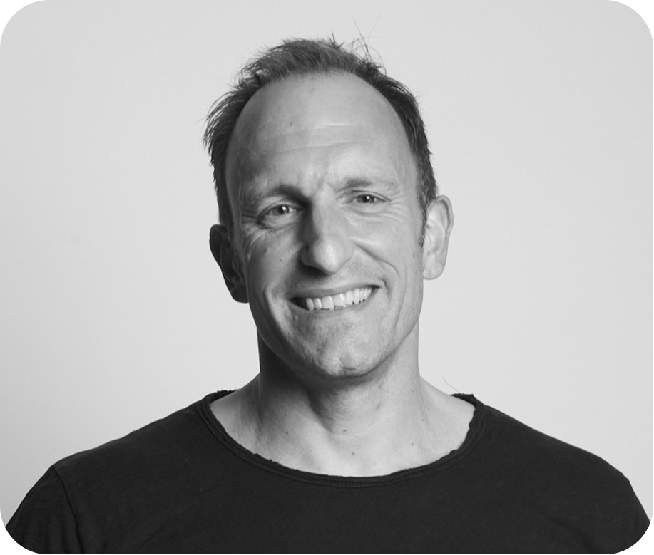 Smiling middle-aged man with short hair wearing a black shirt against a plain background.