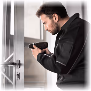 Artisan serrurier Lille 59 en train de visser et remplacer un cylindre de serrure.