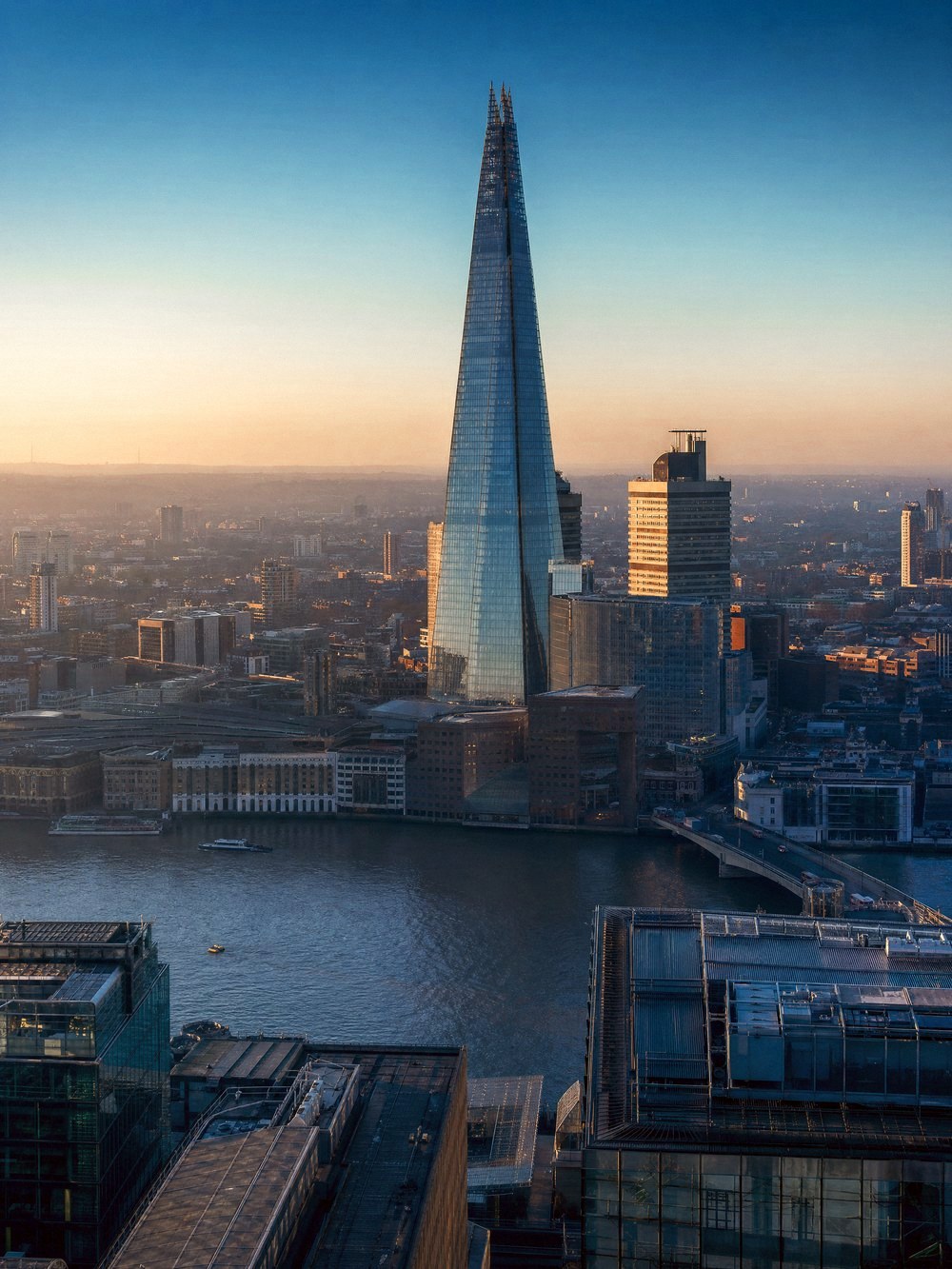 Rooftop view across the City of London at dusk, The Shard rising above the River Thames