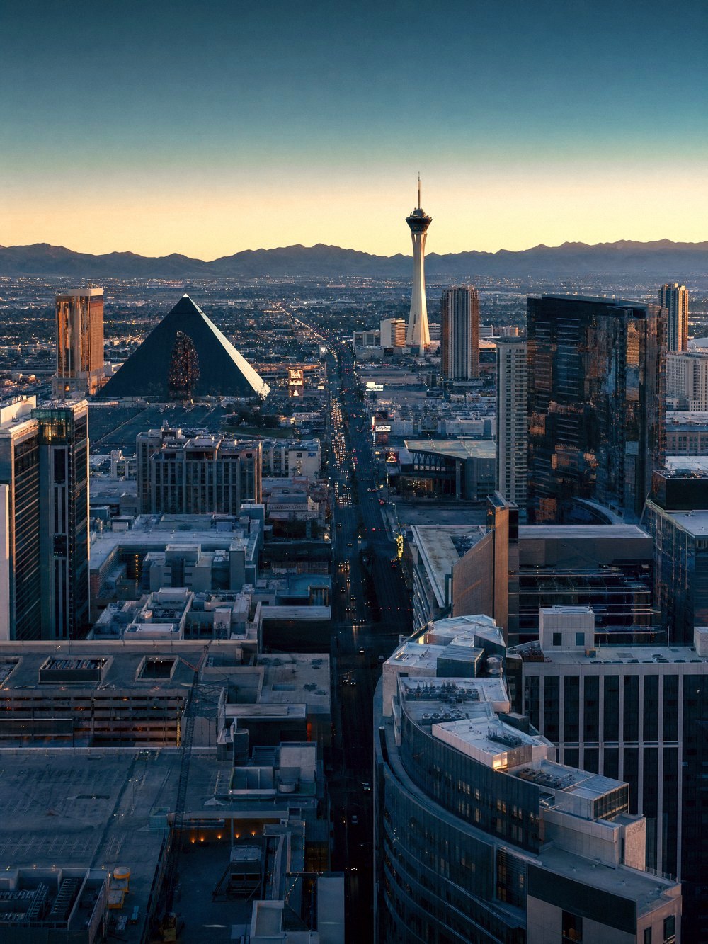 Rooftop view along the Las Vegas Strip at dusk, resort towers and the desert mountains beyond