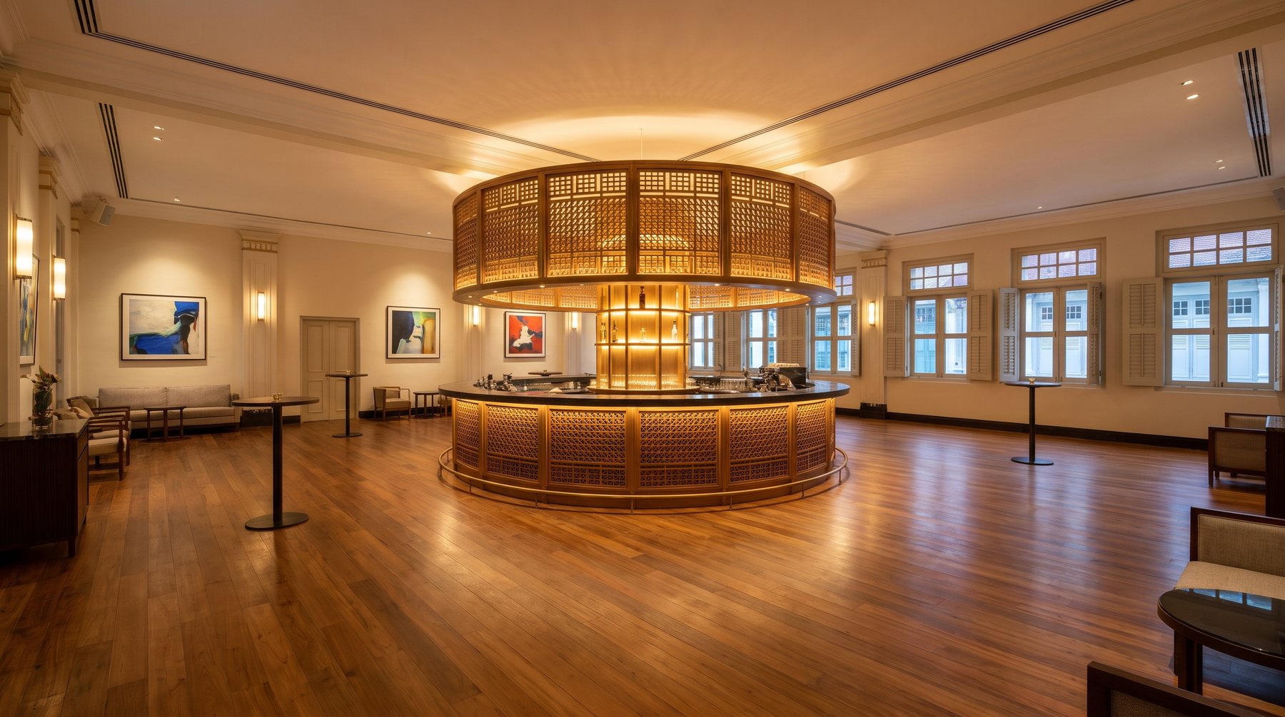 A large, empty parlour in a Singapore heritage shophouse set for a standing reception, a round timber trellis bar at its centre and open floor all around