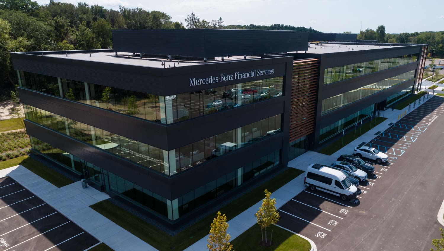 Modern three-story Mercedes-Benz Financial Services office building with large glass windows and adjacent parking lot.