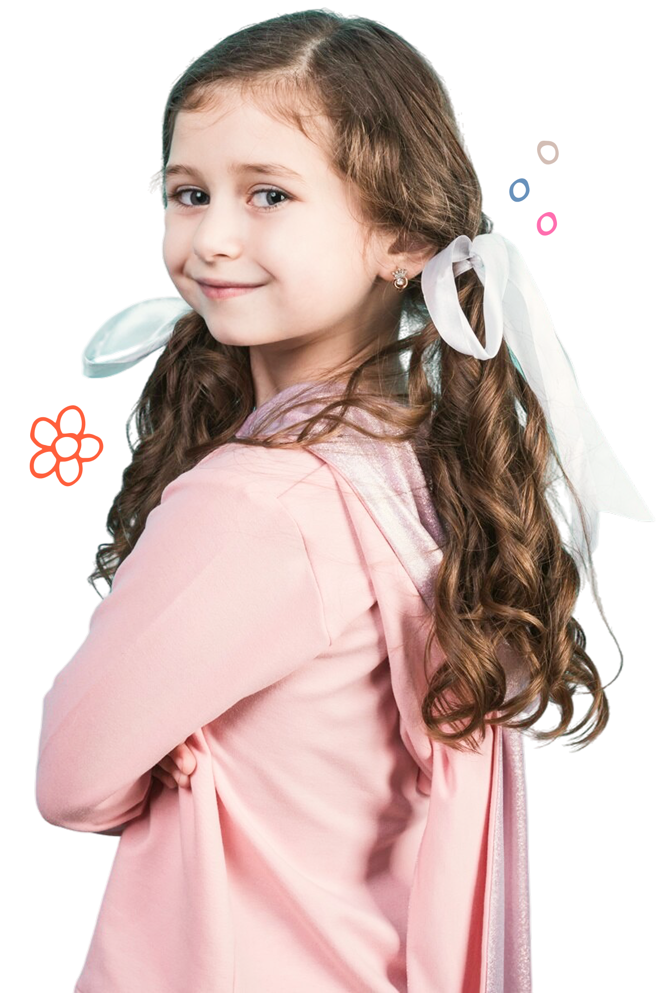 Smiling young girl with curly brown hair tied with white ribbons, wearing a pink hoodie with a cape.