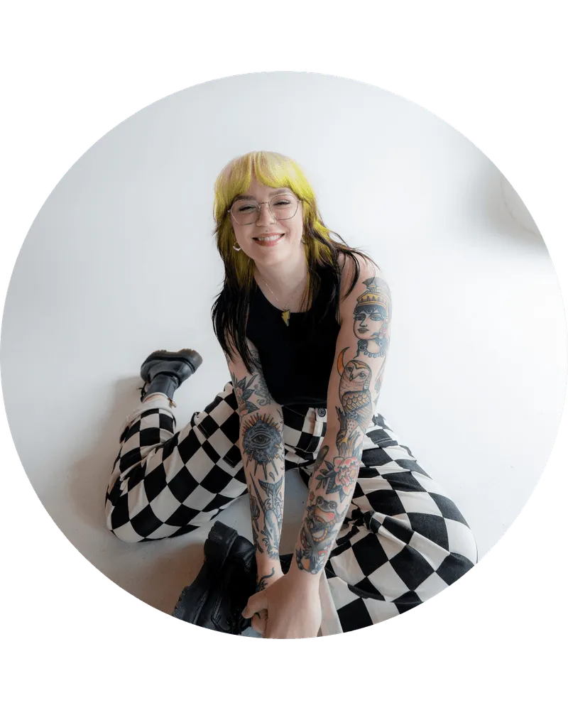 Marci, web designer, sits on the floor and is smiling at the camera.