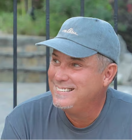 A man smiling with a blue cap and a matching blue T-shirt after downloading Dispute Buddy, an app to download texts for court 