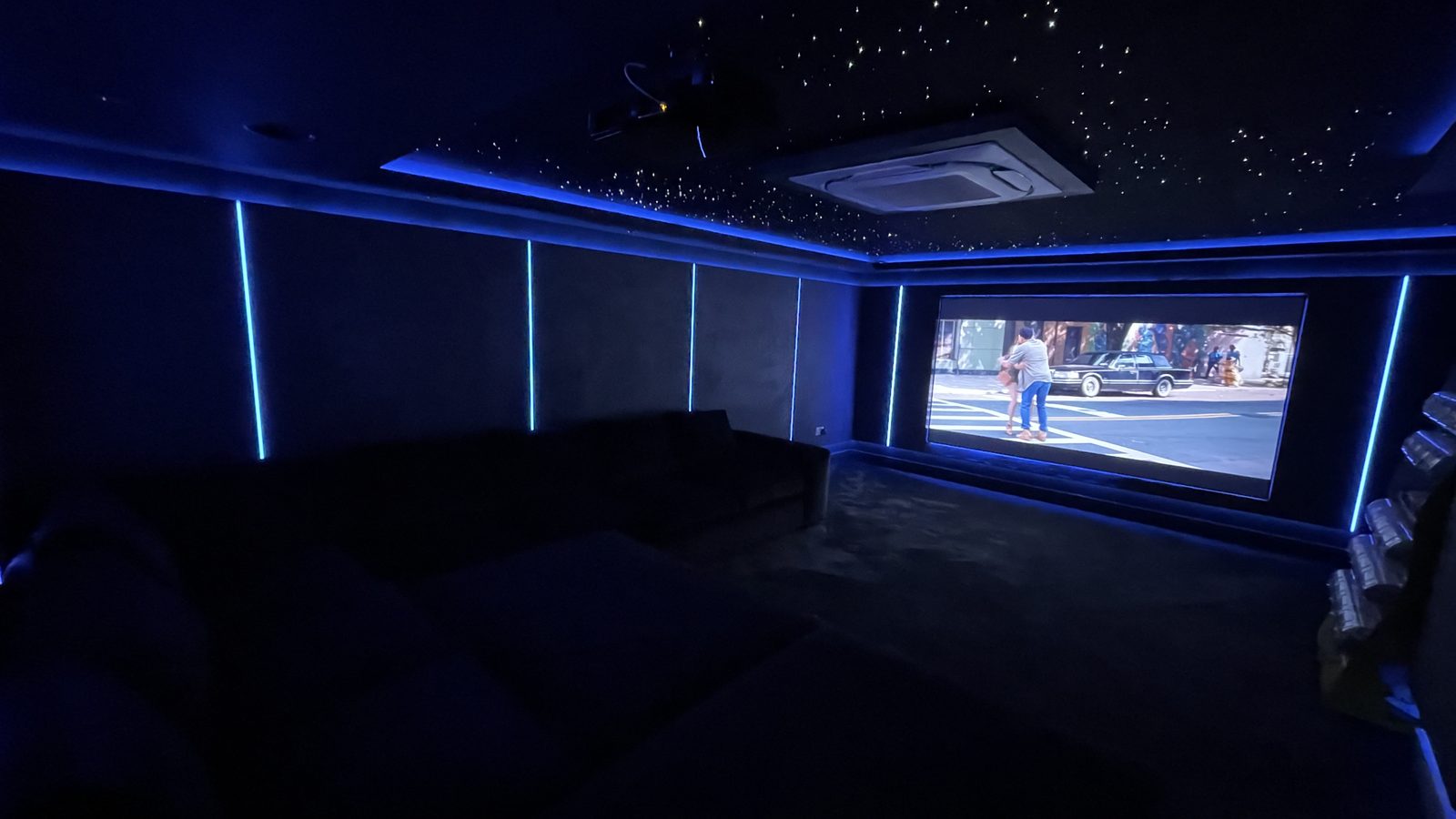 Finished basement home cinema with sofa seating and screen playing a film