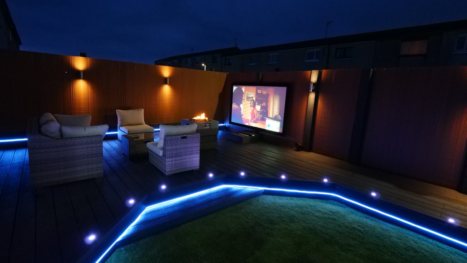Garden room cinema, screen and seating with blue LED lighting at night