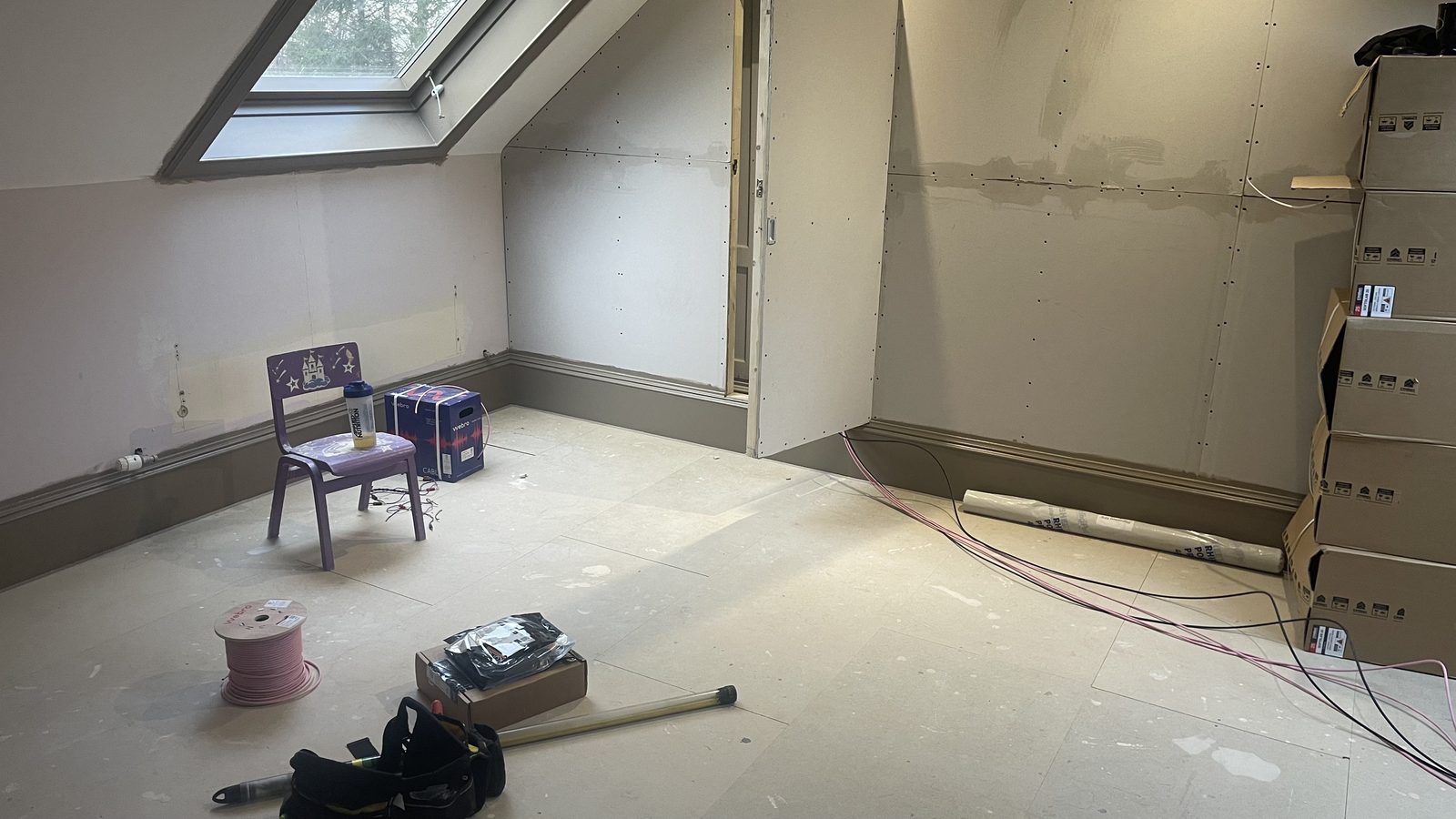Bare attic room with sloped ceiling before cinema conversion