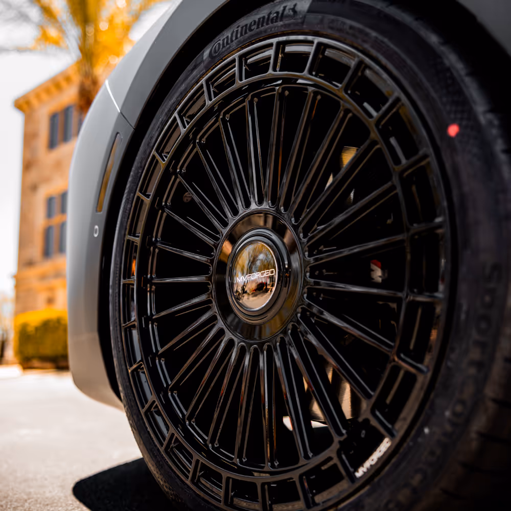 Close-up of a black multi-spoke MVM Forged wheel with Continental tire on a car.