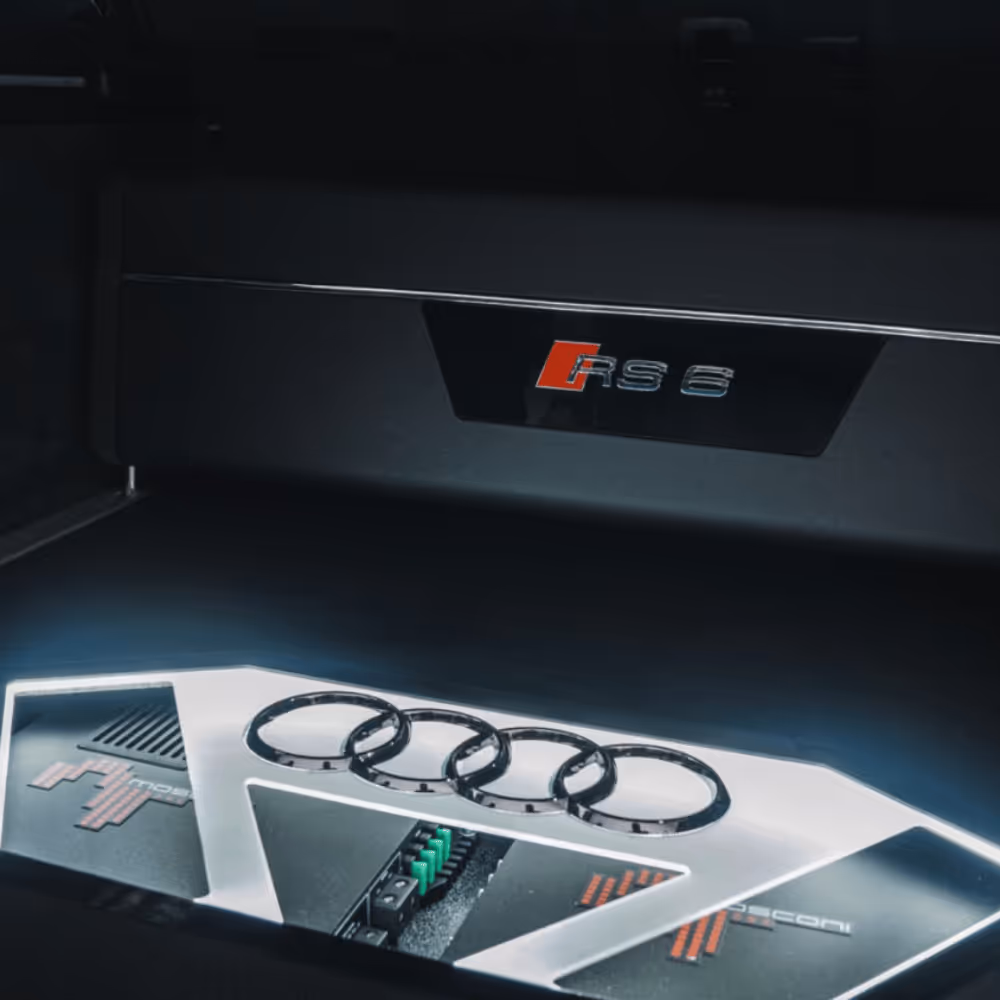 Illuminated Audi RS6 trunk with a custom Focal audio amplifier displaying the Audi rings logo.