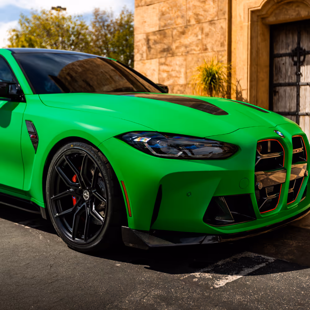 Bright green BMW sports car with black rims parked outside a stone building with a wooden door.