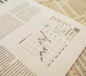Close-up of a financial newspaper page showing a line chart of the U.S. Dollar live exchange rates over several years with accompanying text and data tables.