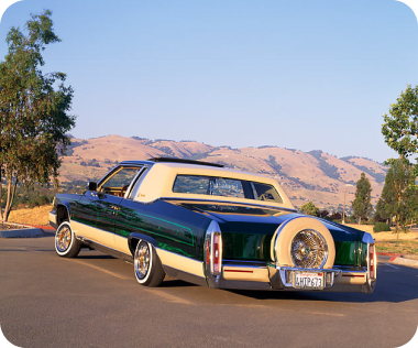 Red Honda Civic coupe with aftermarket modifications parked on pavement with autumn trees and a building in the background.