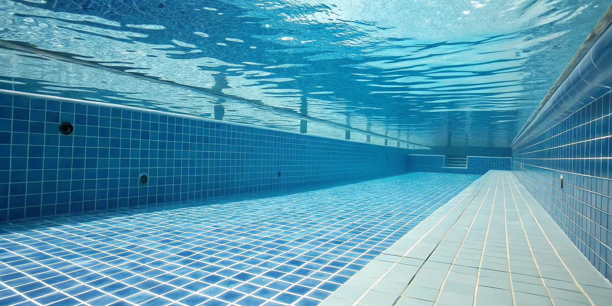 Underwater view of clean blue pool tiles after being cleaned without draining the pool.