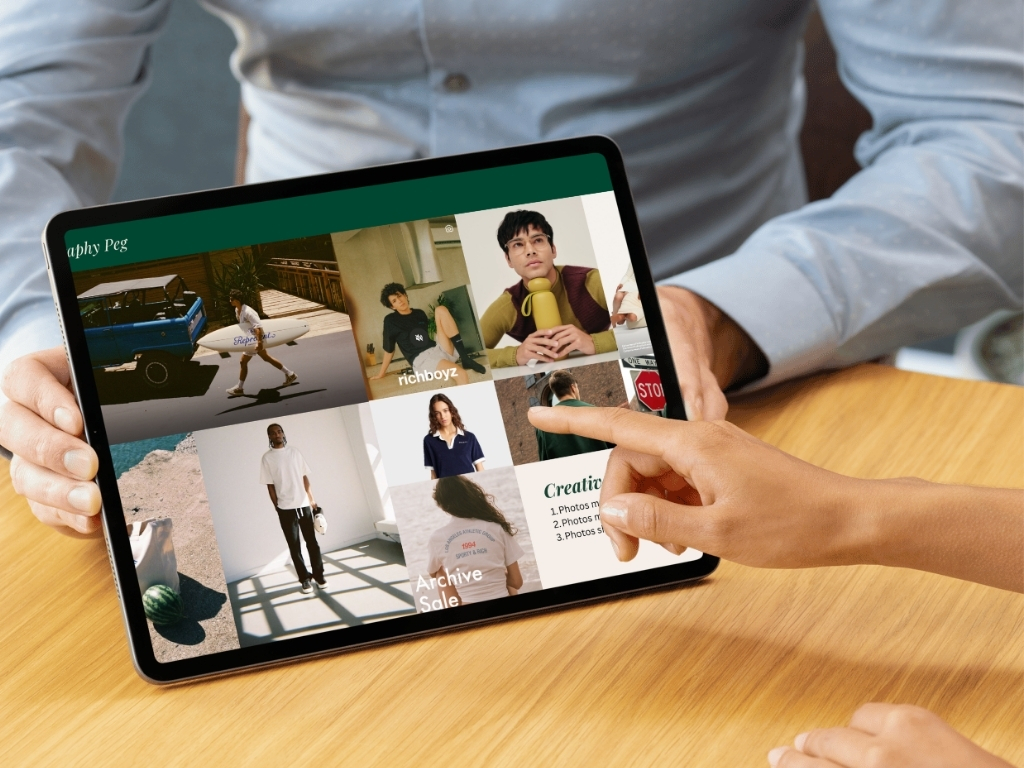 Person holding a tablet displaying a photo portfolio with various images of people and outdoor scenes, another person pointing at the screen.