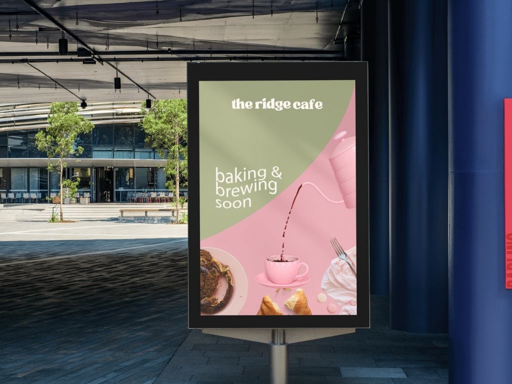 Outdoor digital billboard advertising The Ridge Cafe with the text 'baking & brewing soon,' showing coffee being poured into a pink cup and pastries.