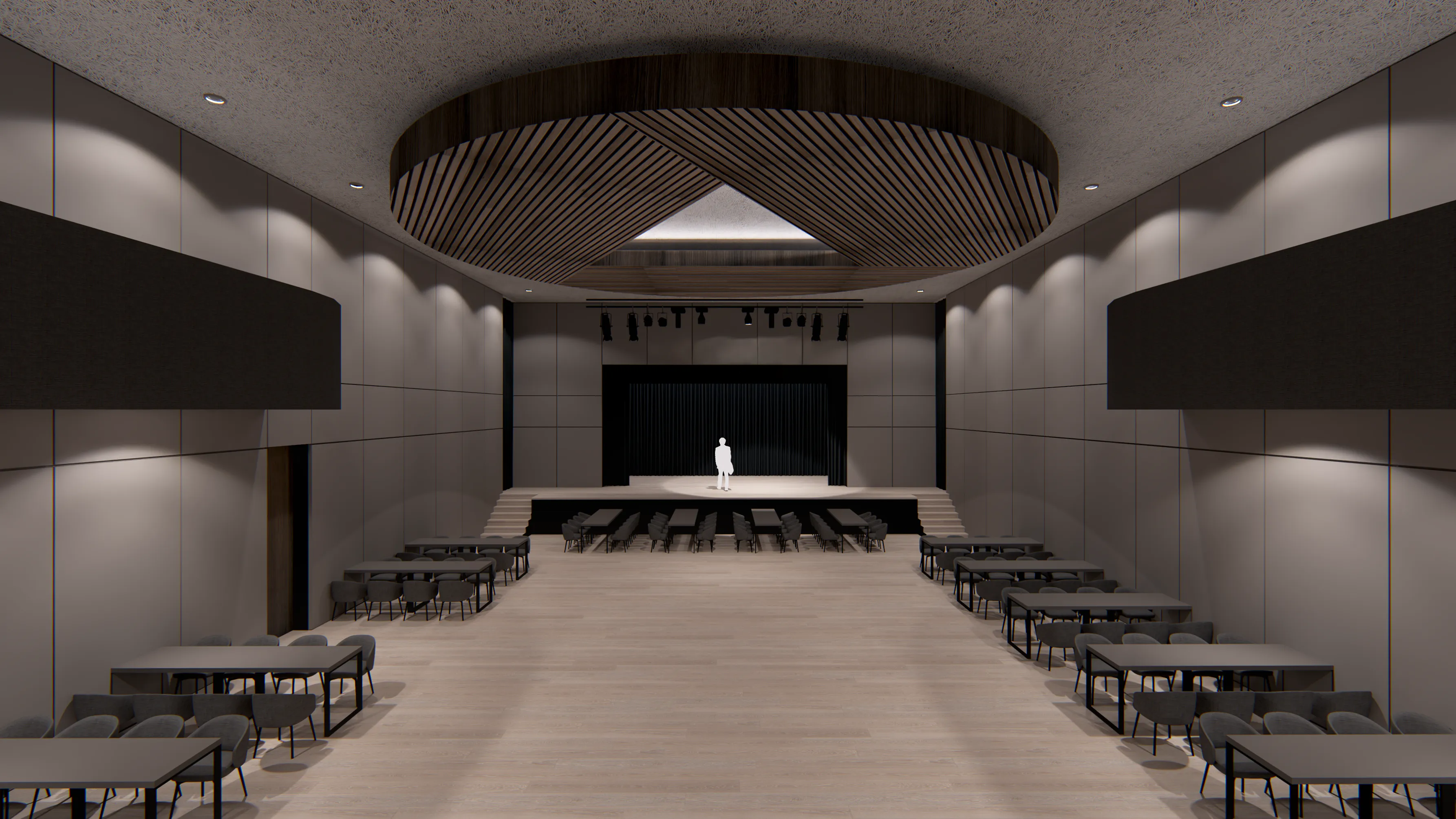 Modern auditorium with wood floor, rows of tables and chairs, a stage with a white silhouette figure, and a large circular wood-accented ceiling feature.