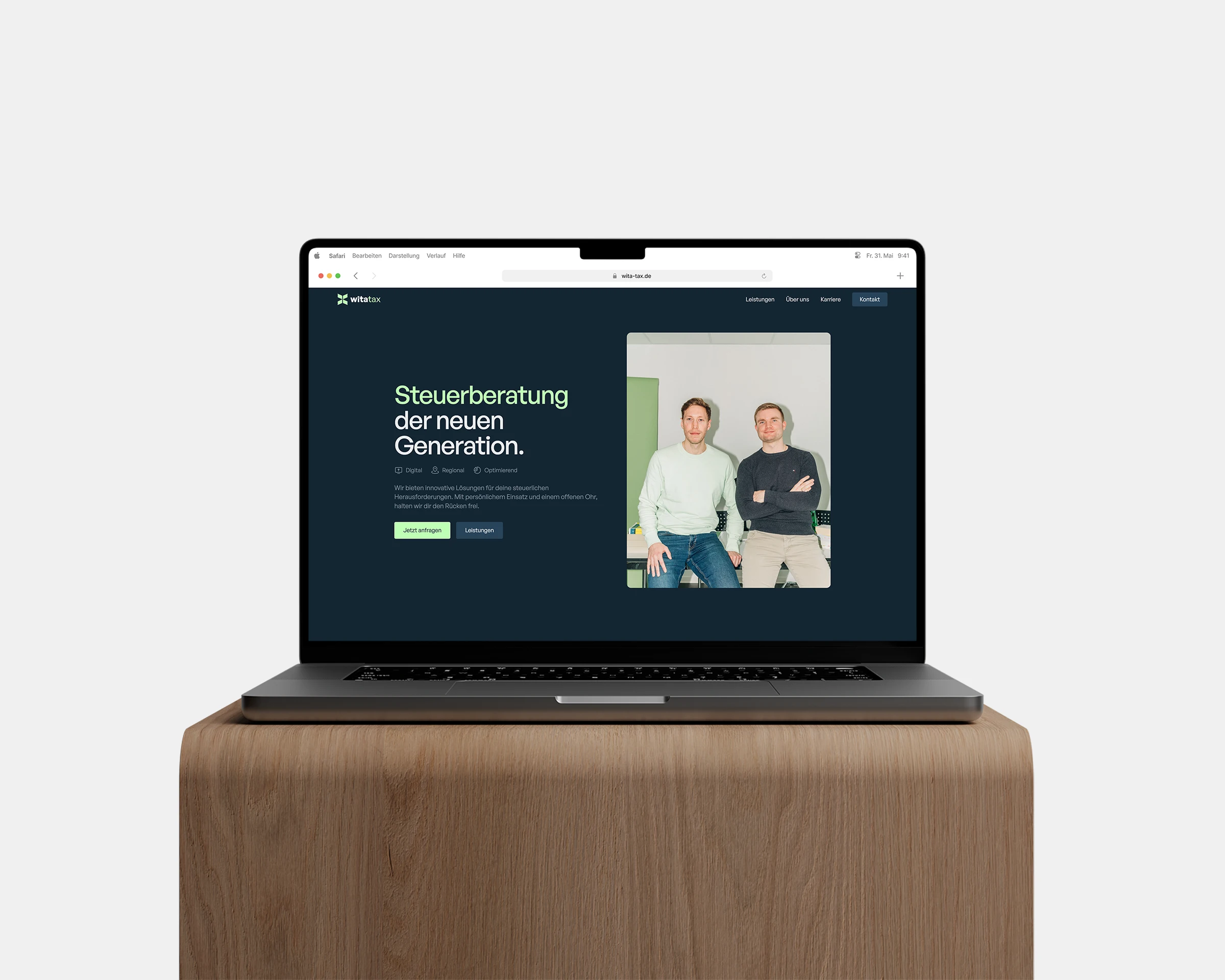 Laptop zeigt eine Website mit dem Text 'Steuerberatung der neuen Generation' und ein Foto von zwei Männern, die nebeneinander sitzen.