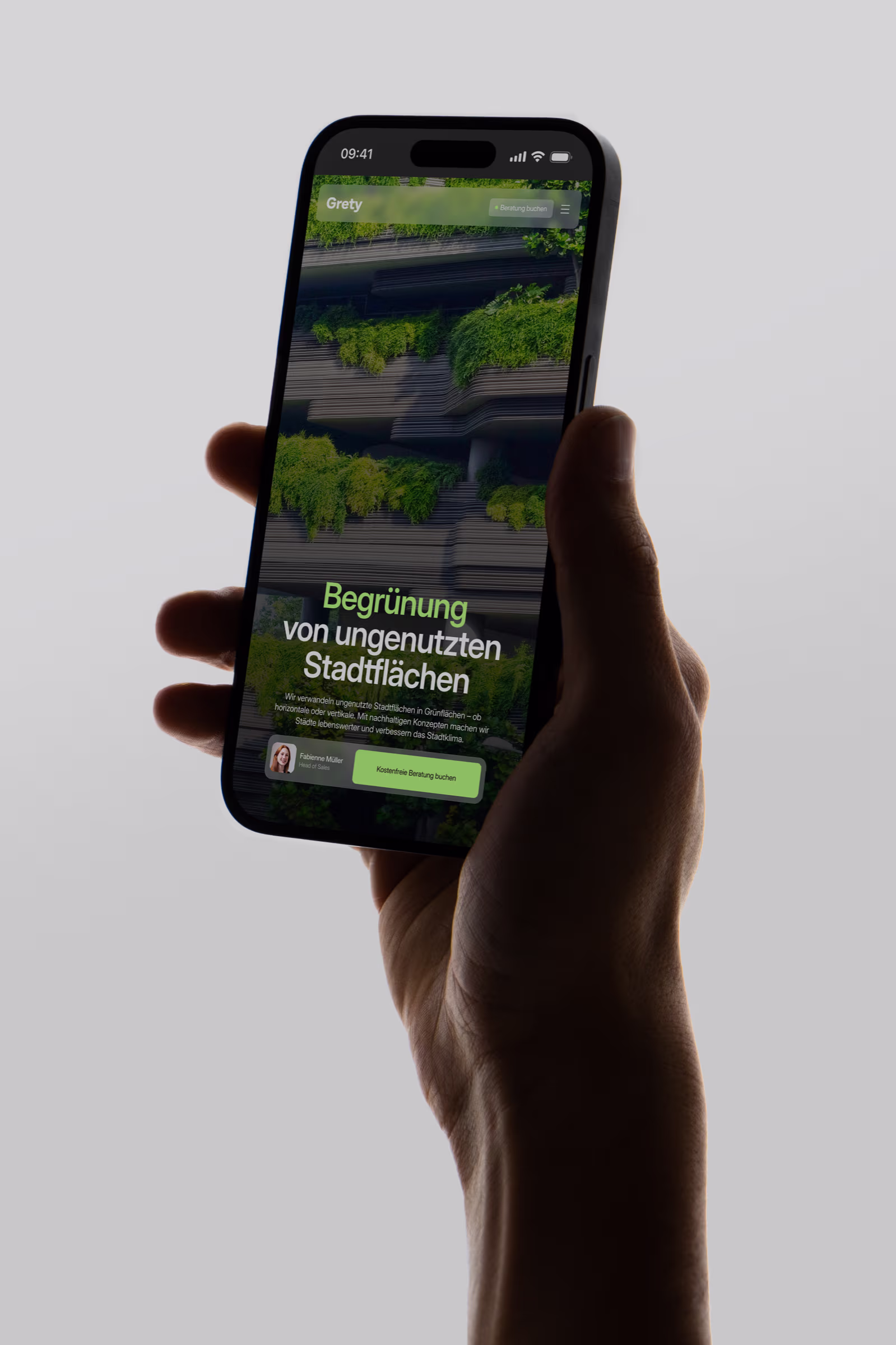 Hand hält ein Smartphone mit einer Website über Begrünung ungenutzter Stadtflächen, grüne Pflanzen an einem Gebäude sichtbar.