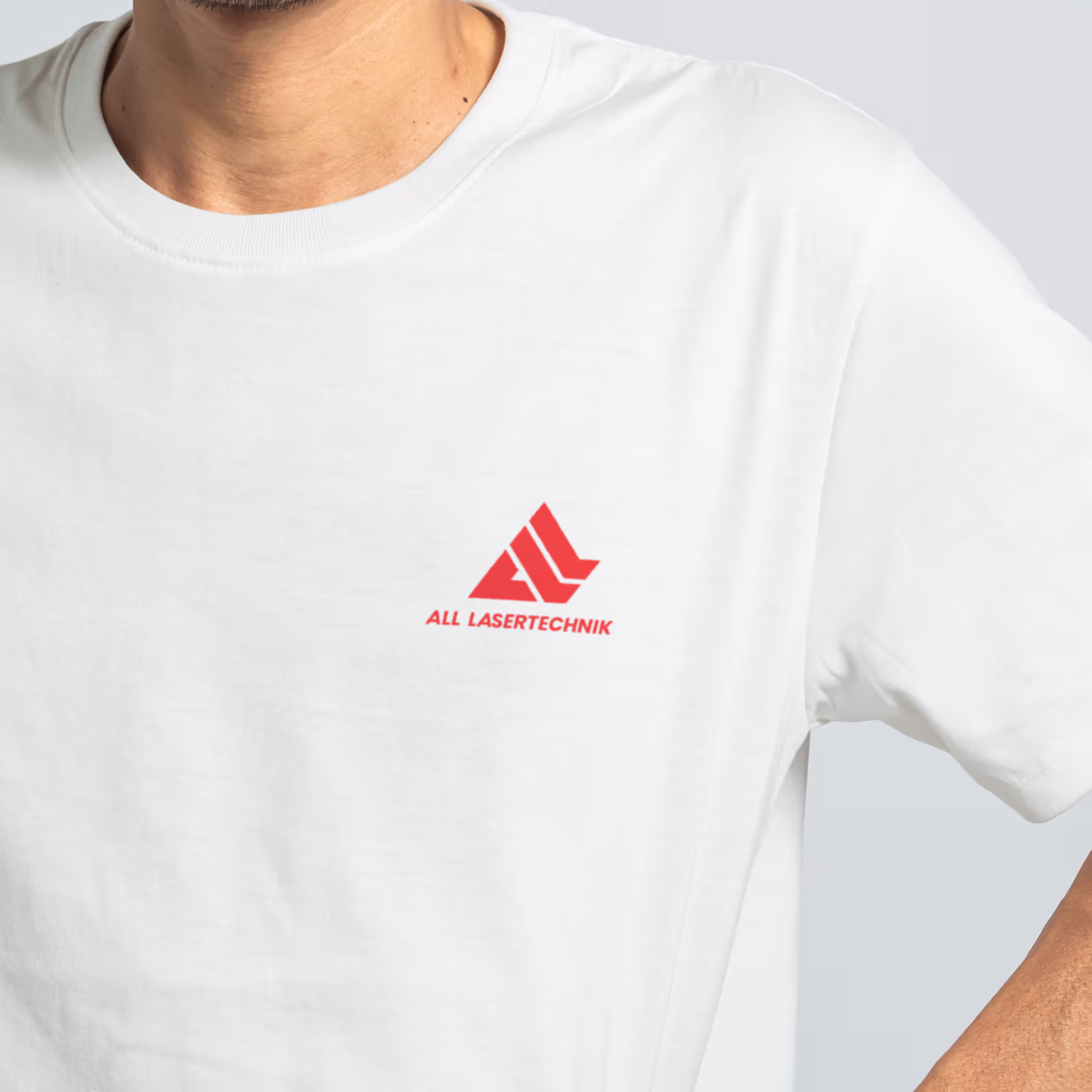Mann trägt weißes T-Shirt mit rotem Logo und Schriftzug „ALL LASERTECHNIK“ auf der linken Brustseite.
