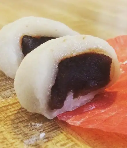 A small mochi, that has been cut in half to show the red bean filling